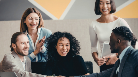 Two finance professionals smiling and collaborating in a bright office, representing ProServeIT's IT services for the finance industry
