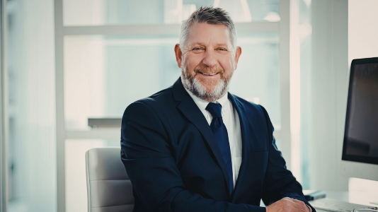 A senior legal professional smiling confidently at his desk, representing ProServeIT's IT services for the legal sector