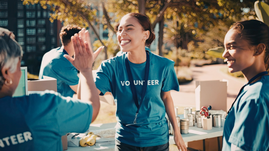 Two volunteers smiling while working together outdoors, representing ProServeIT's IT services for nonprofit organizations