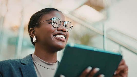 A professional smiling while reviewing content on a tablet, representing ProServeIT's IT services for professional services organizations