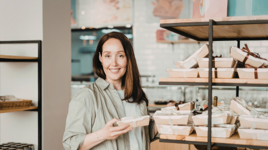A retail professional smiling while managing inventory in a store, representing ProServeIT's IT services for the retail sector