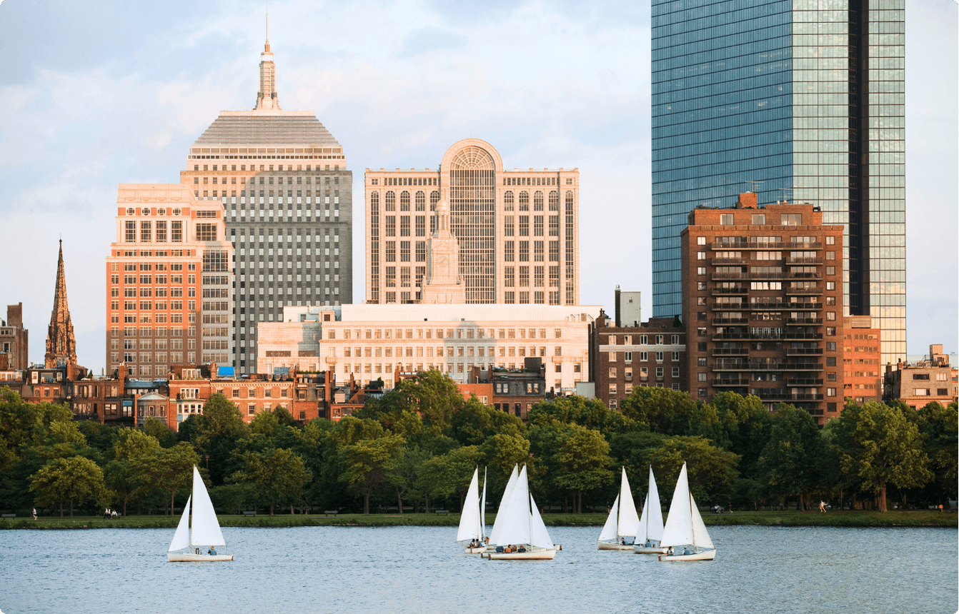 Boston skyline with sailboats on the Charles River and downtown buildings in the background, representing the location of the AI Copilot EBS event.