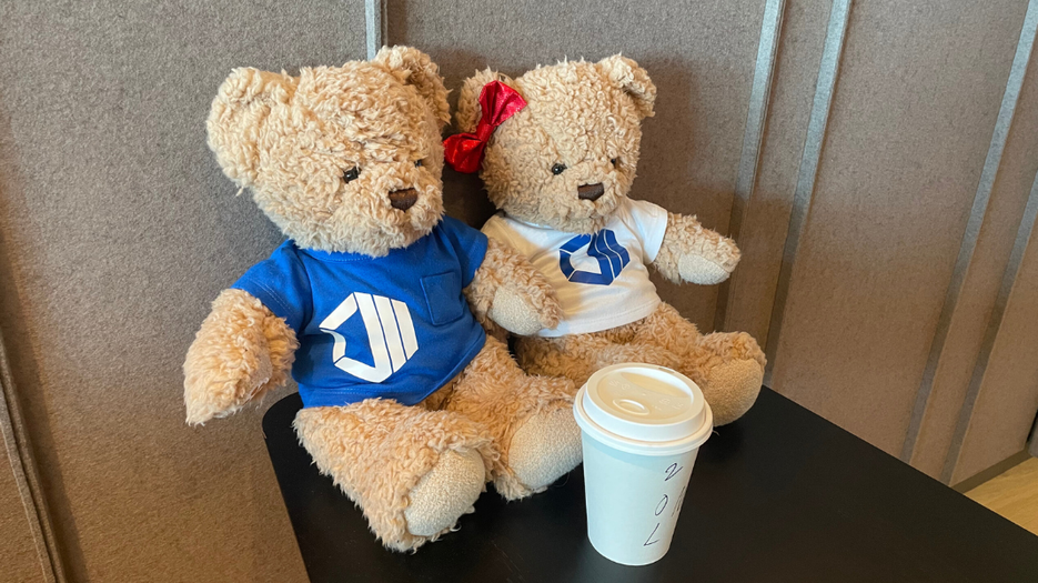 Hope & Hugo as branded teddy bear mascots displayed beside a coffee cup during a company event