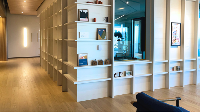 Microsoft office growth mindset library with built-in bookshelves, leadership and business books, open seating areas, and adjacent glass-walled meeting rooms.