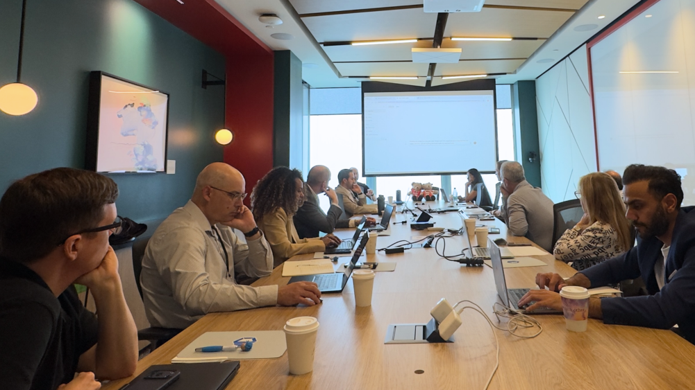 Attendees participating in a ProServeIT AI Executive Briefing Session (EBS) in Toronto, seated around a conference table with laptops in a modern boardroom setting.